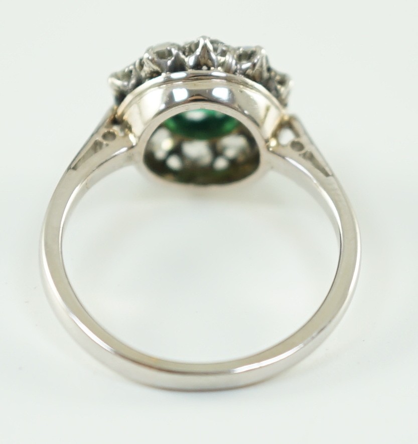 An early to mid 20th century, platinum, octagonal cut emerald and round cut diamond set circular cluster ring